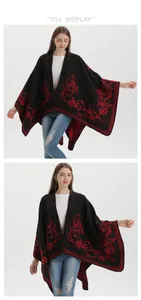 Dettaglio di scialle in maglia nera con ricamo floreale rosso e bordo asimmetrico