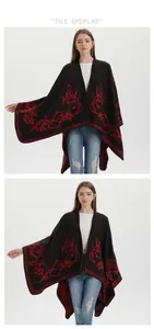 Dettaglio della mantella in maglia nera con ricami rossi di fiori e uccelli