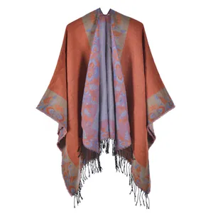 Detail of bohemian floral knit poncho with fringed edges in warm rust red and blue