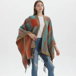 Plaid oversized knit poncho with fringe details in blue and orange geometric patterns