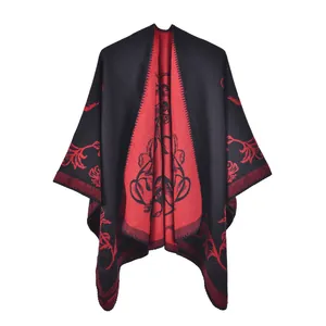 Détail du motif floral rouge et noir sur un poncho réversible en imitation cachemire