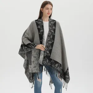 Women knit poncho with retro floral patterns and fringe hem on a grey background