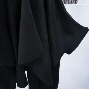 Detail shot of black hooded shawl cape with premium textured knit fabric and edge stitching