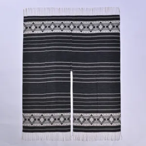 Detail of bohemian geometric knit poncho with long cream tassels and split-front design
