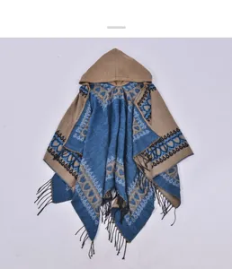 Close-up of geometric jacquard knit poncho featuring fringe trim and cozy hooded design
