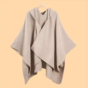 Detail view of knitted hooded shawl featuring beige textured weave and hem stitching