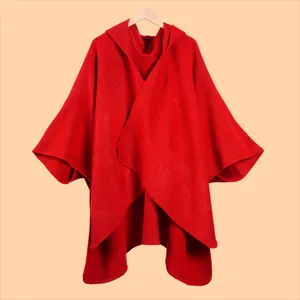 Detail of red hooded poncho cape featuring thick knitted texture and clean edge stitching