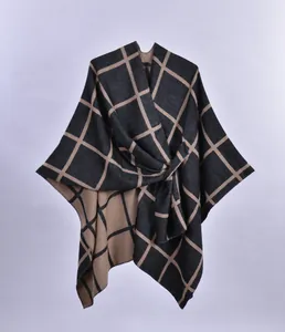 Detail of classic plaid knitted poncho with elegant knot drape and thick texture