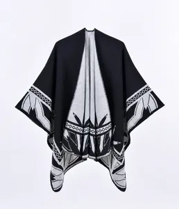 Detailansicht eines dicken Strickponchos mit grauen geometrischen Mustern auf schwarzem Stoff