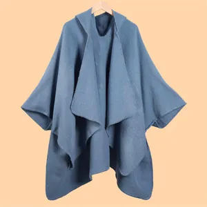 Detailed close-up of gray-blue knit poncho showing refined edge stitching on wooden hanger