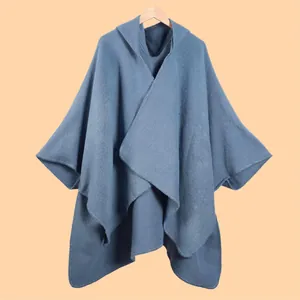 Detail of blue hooded poncho cape with knitted texture and high-quality lockstitch edges