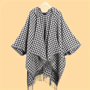 Detail view of stylish houndstooth shawl with long decorative fringe and knit texture