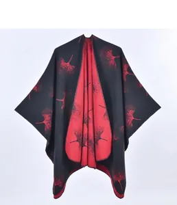 Dettaglio di un poncho a maglia con motivi di foglie di ginkgo rosse su fondo nero