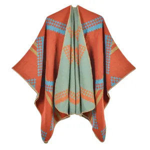 Knit shawl poncho with brick red geometric patterns and decorative blanket stitch