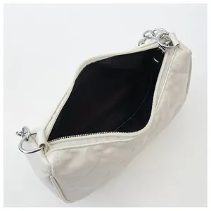 Détail d'un sac à main blanc matelassé avec fermeture éclair argentée et doublure noire