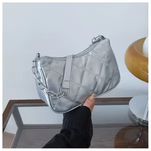 Détail du sac matelassé argenté montrant les coutures précises et la chaîne en métal