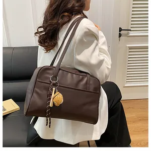 Detail of dark brown faux leather tote bag with unique baseball and bat charm accessory