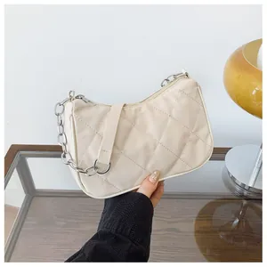 Détail d'un sac à bandoulière matelassé beige avec chaîne argentée et fermeture éclair