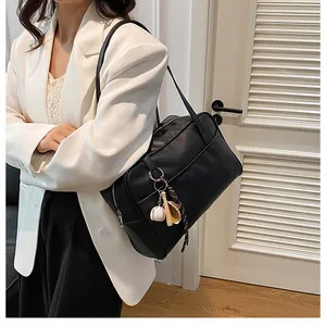 Detail of black matte faux leather tote bag with unique baseball keychain accessory