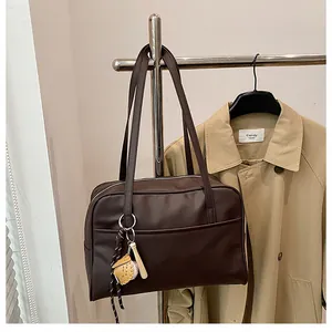 Detail of a dark brown Boston shoulder bag with a unique baseball bat pendant accessory