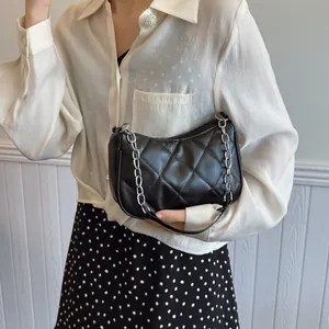 Sac sous le bras matelassé noir élégant avec bandoulière chaîne porté par un mannequin