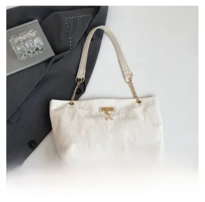 Detail showing the pleated cream texture, golden chain strap, and deer pendant on the bag