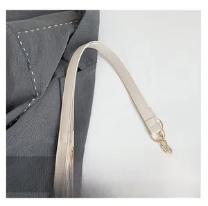 Close-up of cream faux leather strap with gold chain links on a shoulder bag