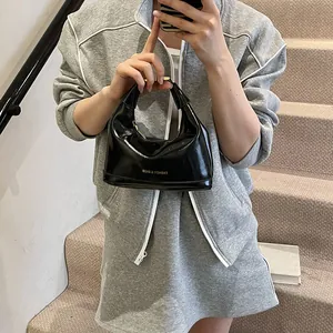 Sac à main chic en cuir verni noir brillant avec fermeture éclair dorée et poignée