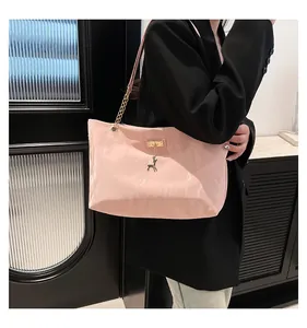 Detail of pink shoulder bag featuring a gold chain strap and elegant deer pendant