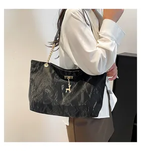 Close-up of black pleated texture shoulder bag featuring gold deer pendant and chain