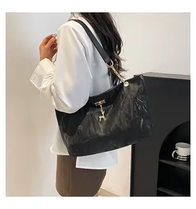 Detail of black tote bag with unique wrinkled texture and gold chain shoulder strap
