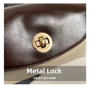 Nahaufnahme der Lederstruktur mit hochglänzendem goldenem Metallschloss der Umhängetasche