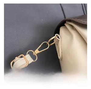 Detailaufnahme des hochwertigen Gold-Metallhakens und beigen Lederriemens an der Tasche