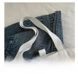 Close-up of white canvas tote bag handles with durable reinforced stitching details