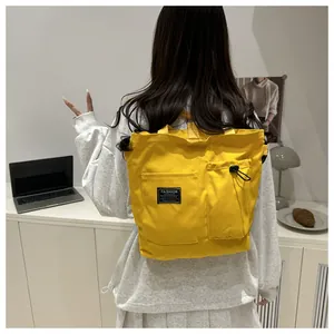 Detail view of a yellow canvas backpack with drawstring pockets and fashion label