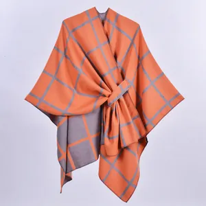Dettaglio dello scialle in maglia a quadri arancio e grigio con trama jacquard double-face