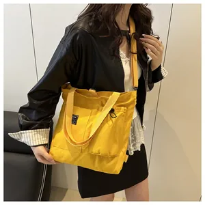 Detail of yellow canvas tote bag with multiple pockets and fashion label on a model
