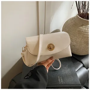 Detail einer cremeweißen Kunstledertasche mit goldenem Drehverschluss in der Hand