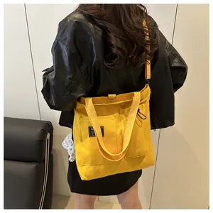 Close-up of yellow canvas tote bag with fashion patch and adjustable shoulder straps