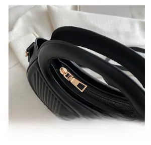 Detail shot of golden smooth zipper and pleated texture on black handbag