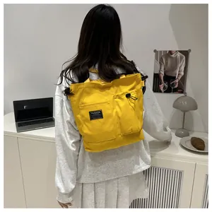 Close-up of bright yellow canvas tote bag with drawstring pockets and fashion label detail