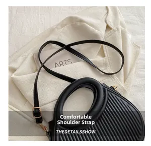 Detail of black PU leather handbag with ripple texture and gold-tone hardware accents