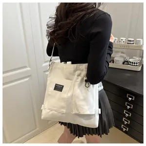 Detail of white canvas tote bag featuring double front pockets and Fashion Instinct label