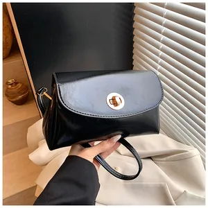 Nahaufnahme der schwarzen Ölwachsleder-Handtasche mit Hochglanz-Finish und Golddrehverschluss