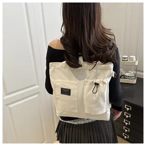 Close-up of white canvas tote bag featuring dual front pockets with drawstrings