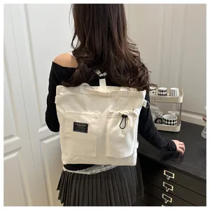 Detail of cream canvas backpack featuring double front pockets and drawstring structure