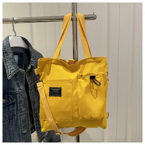 Detail of bright yellow canvas tote featuring a drawstring pocket and woven fashion label