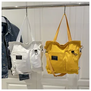 Detail of white and yellow canvas tote bags with adjustable straps and front pockets