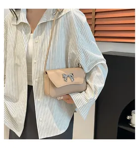 Dettaglio borsa a tracolla beige con fibbia a fiocco argento e sottile tracolla in pelle