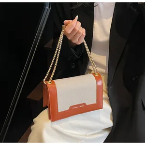 Detail einer schicken Ketten-Handtasche aus orangefarbenem Kunstleder und Webstoff